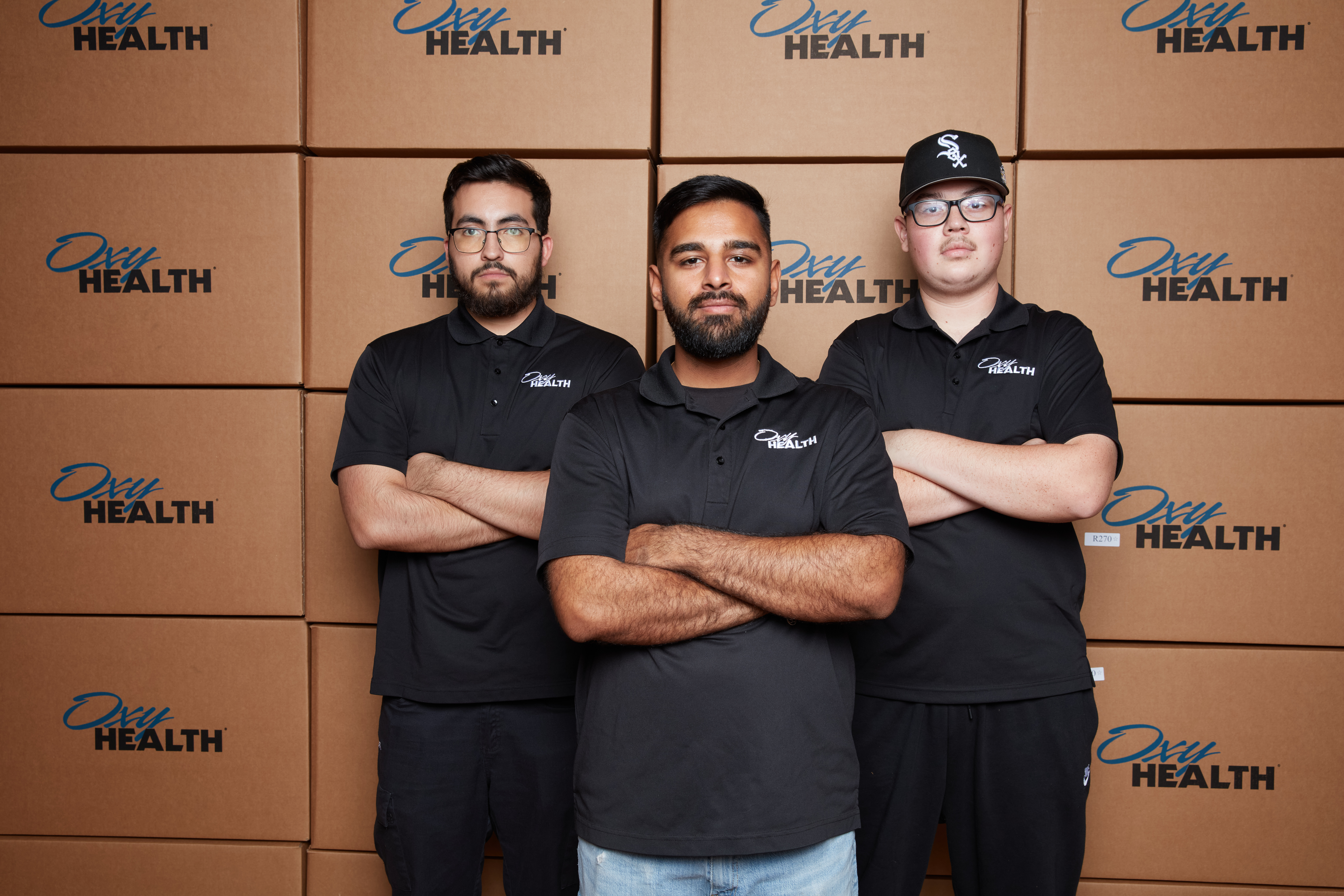 OxyHealth warehouse team with branded shipping boxes preparing hyperbaric chamber components for service and delivery